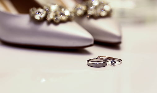 silver-colored ring next to pair of silver shoes