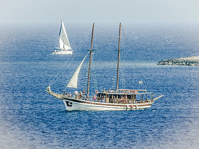 photo of white sail boat on body of water