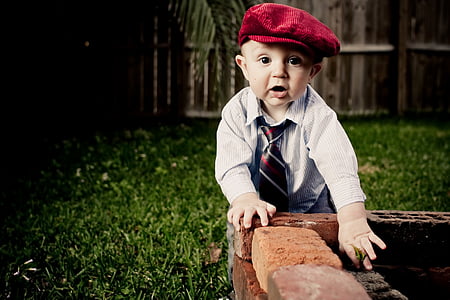 toddler boy standing on brown bricked bench