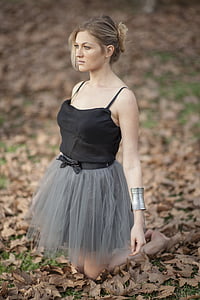 photography of kneeling woman wearing black spaghetti-strap top and green skirt