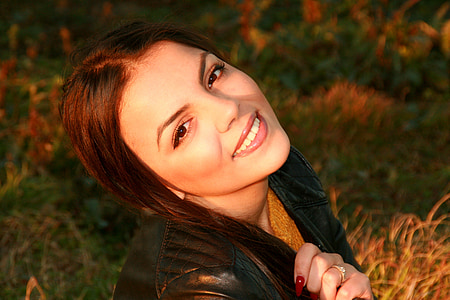 smiling woman wearing black leather jacket holding hair