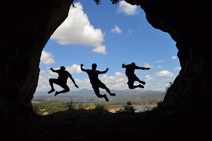 silhouette photo of three person hopping