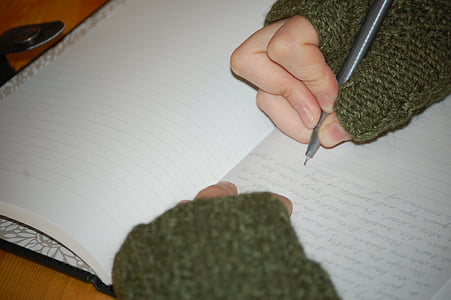 person wearing green long-sleeved shirt when writing on notebook