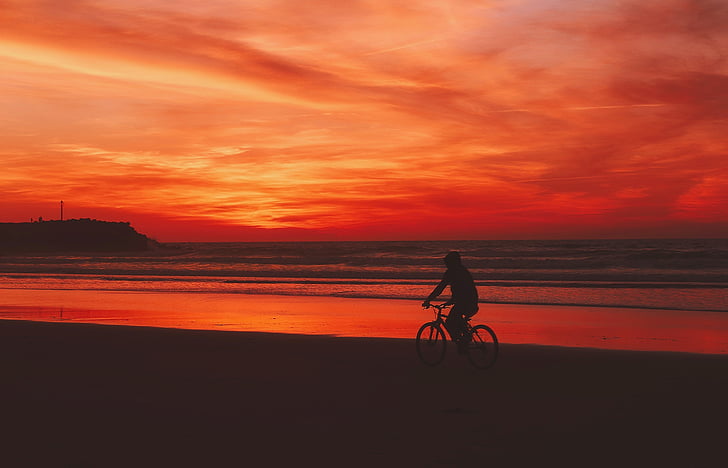 person riding on bike under sunset