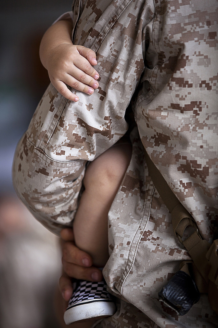 close up photograph of man in military jacket holding baby