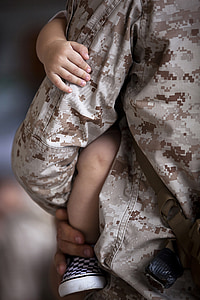 close up photograph of man in military jacket holding baby