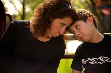 boy in black shirt beside woman sitting on bench