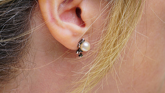 person taking a photo of unpaired white pearl stud earring