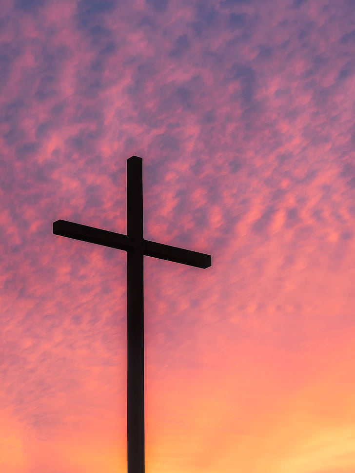 silhouette of cross taking photo during golden hour
