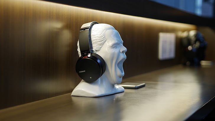 black wireless headphones on white person's head figurine