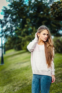 woman wearing sweater standing on green field