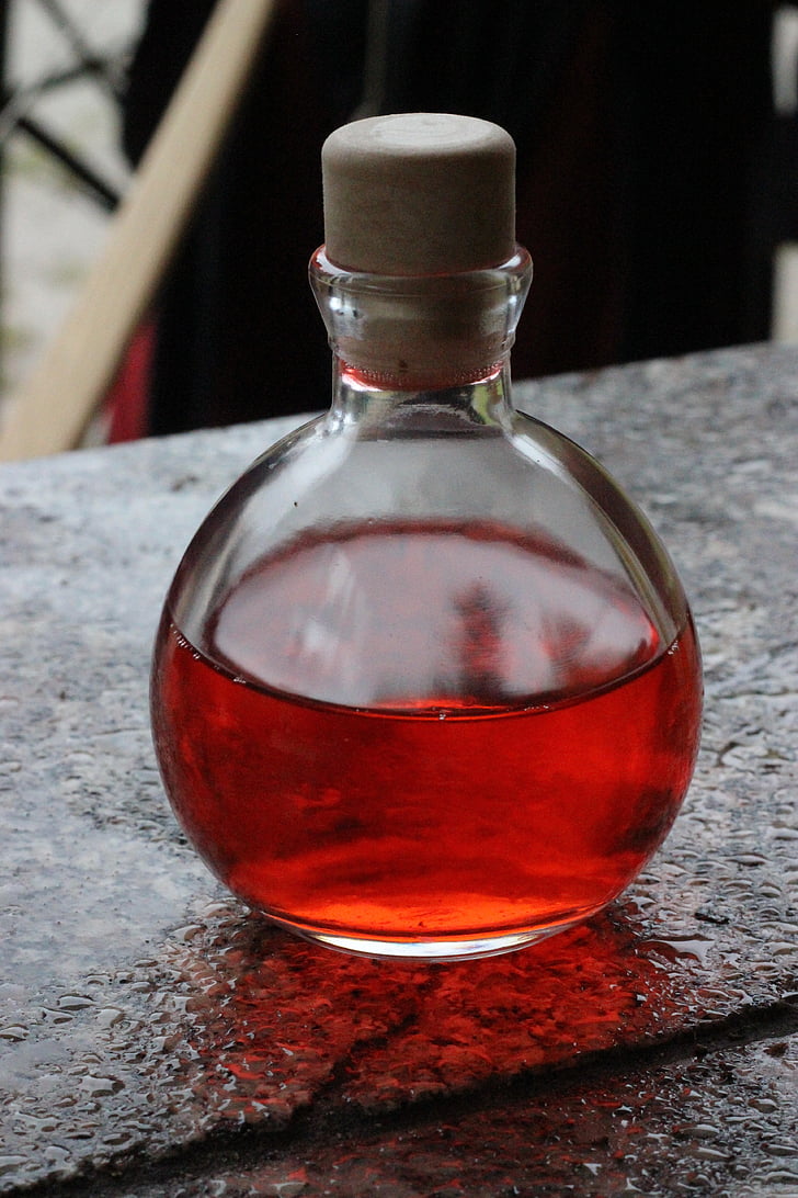 close-up photo of clear glass bottle with red liquid