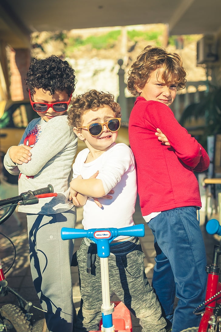 three boy standing in front of their bicycles and scooters