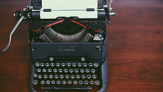 photo of black typewriter on brown wooden surface