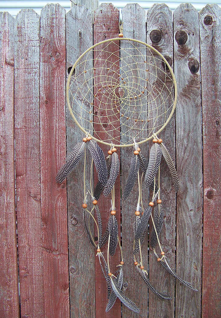 brown and gray dreamcatcher hanged on brown wooden fence