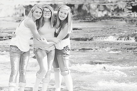grayscale photography of three standing women beside body of water