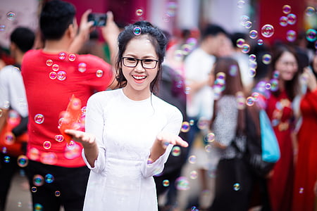 selective focus photo of woman surrounded with bubbles located in the crowd during daytime