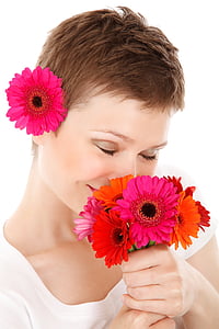 woman holding gerbera daisies while smelling it