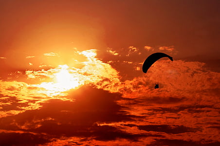 person riding parachute near clouds