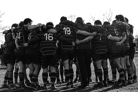 grayscale photography of group of men in huddle
