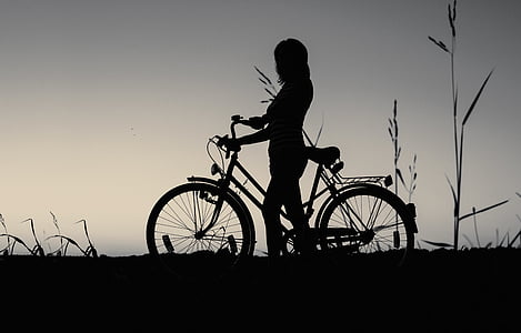 silhouette photograph of person holding bicycle