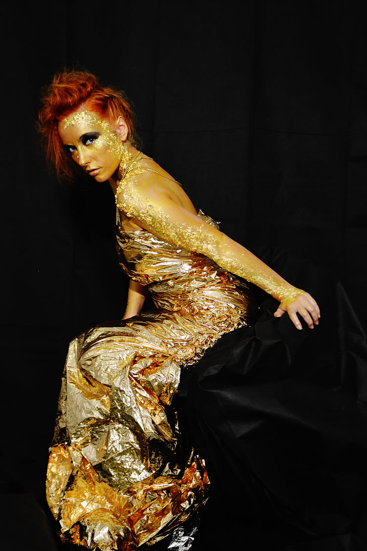 woman wearing gold long-sleeved dress with black background