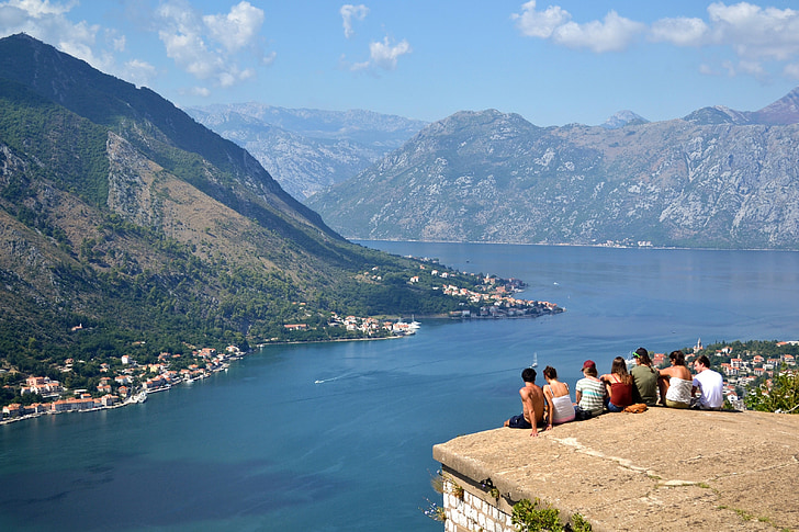 group of people sitting on cliff during daytime