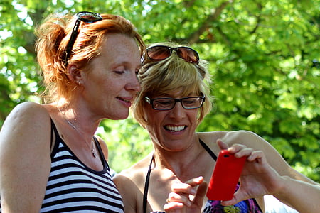two woman both watching at phone's screen
