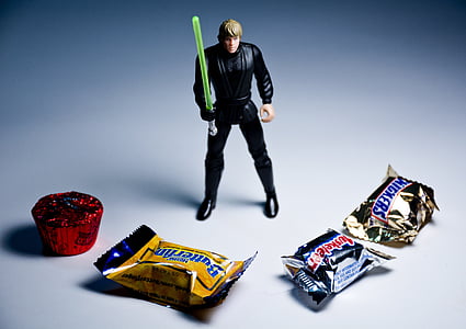 Luke Skywalker action figure behind four assorted-brand chocolate packs