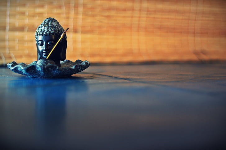 close-up photography of buddha black ceramic figurine on black surface