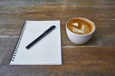 black pen on spiral notebook beside cappuccino art