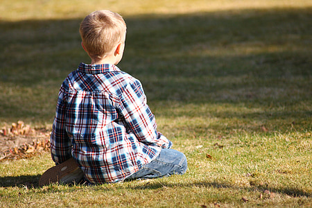 boy sitting on green grass