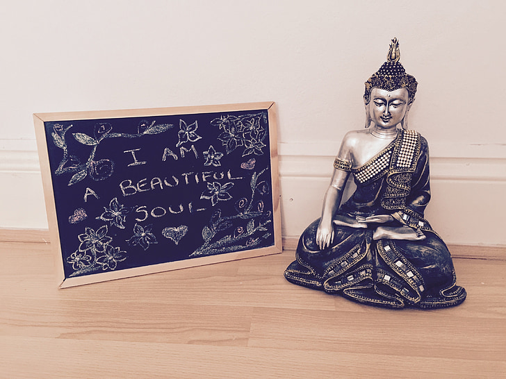 silver-colored Gautama Buddha figurine and black board