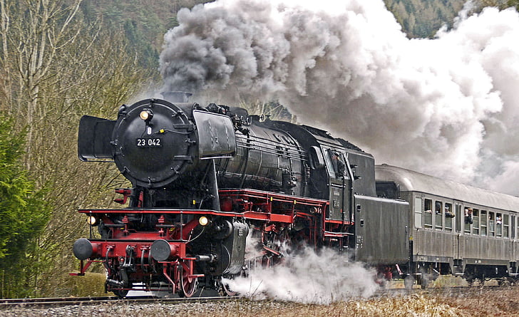 moving black locomotive train covered with thick smoke