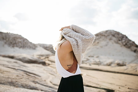 woman in white tank top covering her head with brown knit sweater photo taken during daytime