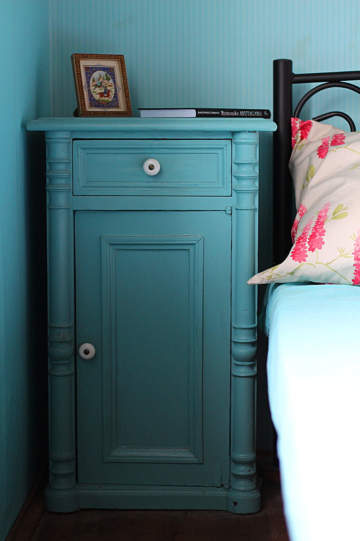 blue wooden cabinet beside black bed
