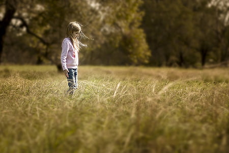 girl in pink hoodie standing in grass field
