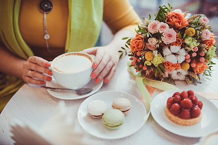 white ceramic cup on white saucer beside flower bouquet