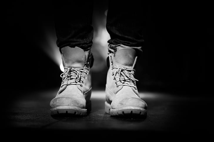 grayscale photography of person wearing pair of boots
