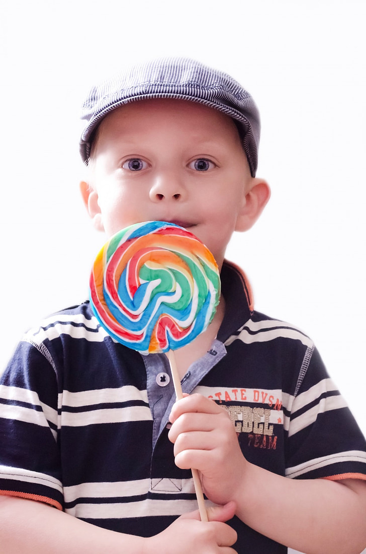 boy wearing black and white striped polo shirt holding lollipop