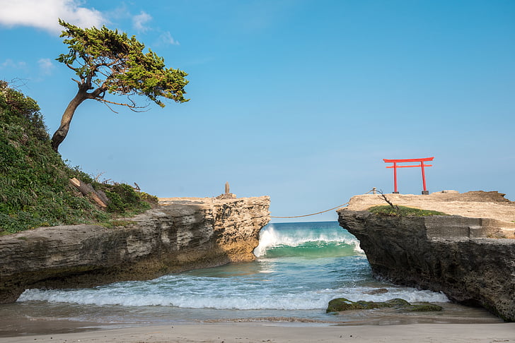 torii arch on top of cliff under clear skies during daytime