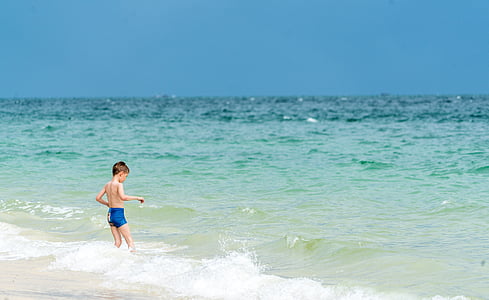 boy on seashore standing during daytime
