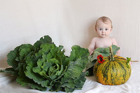 baby in front of cabbage and squash