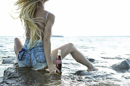 woman wearing short shorts holding Coca-Cola bottle