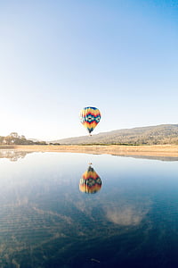 yellow and blue hot air balloon over calm body of water