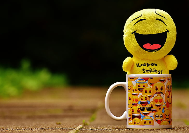 smiling emoji plush toy on emoji print mug