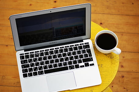 MacBook Air beside cup of coffee
