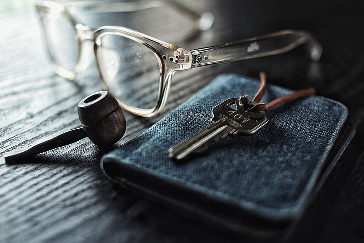 eyeglasses beside gray steel key