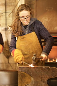 woman hitting metal with hammer