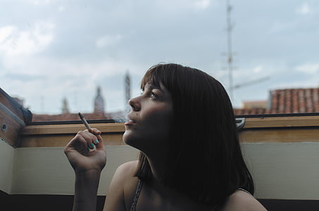 woman sitting while holding cigarette